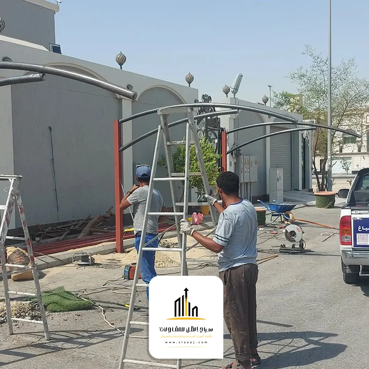 فريق من حدادين مظلات الرياض من سياج الظل وهم يقومون بتركيب مظلة بدقة واحترافية، مع التركيز على السلامة والجودة في كل خطوة.